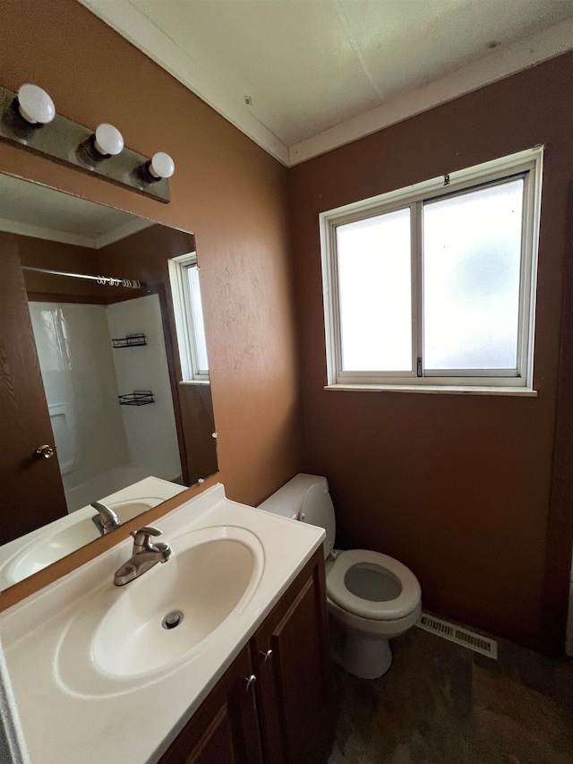 bathroom featuring a wealth of natural light, vanity, and toilet