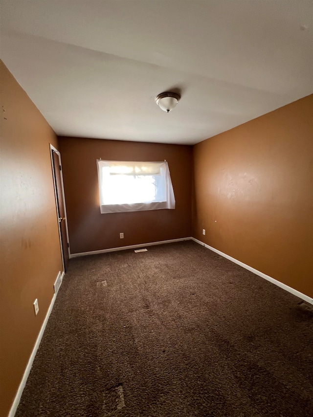 unfurnished room featuring dark carpet