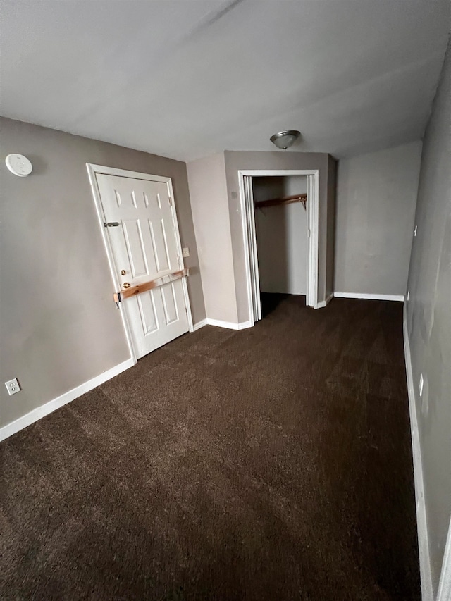 unfurnished bedroom featuring dark colored carpet and a closet