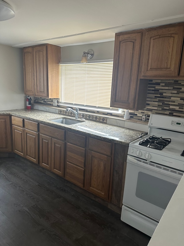 kitchen with white range with gas stovetop, dark hardwood / wood-style flooring, tasteful backsplash, and sink