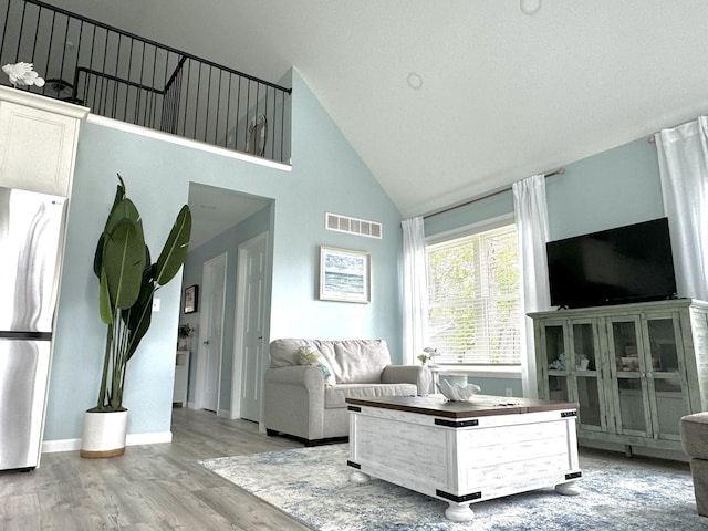 living room with high vaulted ceiling and light wood-type flooring