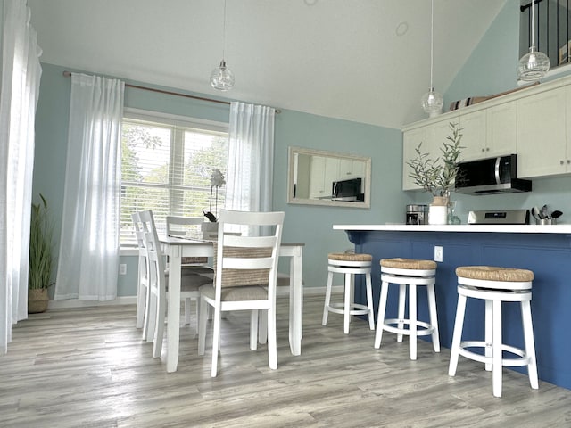 dining room featuring high vaulted ceiling and light wood-type flooring