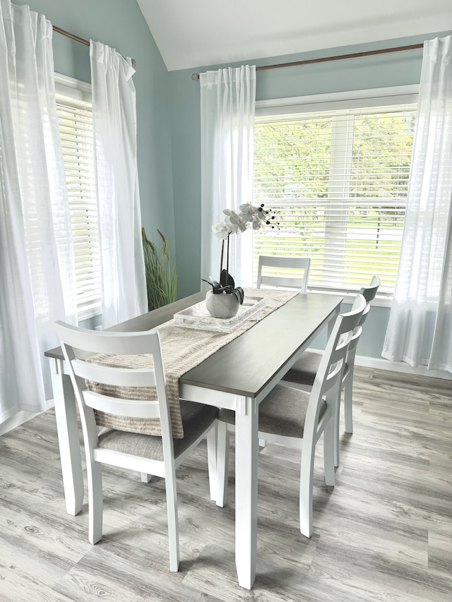 dining room featuring a wealth of natural light, vaulted ceiling, and light wood-type flooring