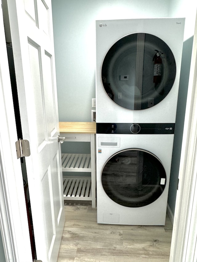 laundry area with stacked washer and dryer and light hardwood / wood-style floors