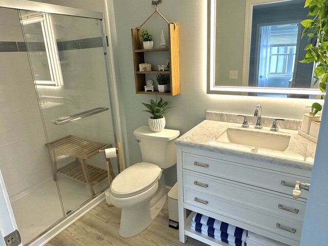 bathroom with toilet, an enclosed shower, wood-type flooring, and vanity