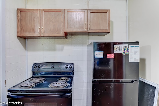 kitchen featuring decorative backsplash, black range with electric cooktop, and refrigerator