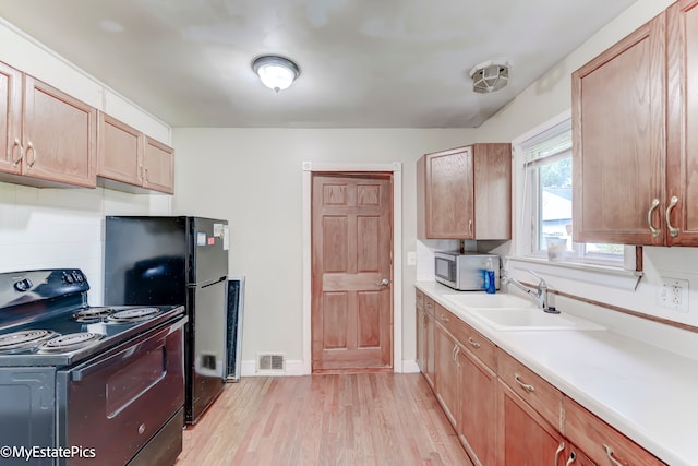 kitchen featuring sink, black appliances, and light hardwood / wood-style floors