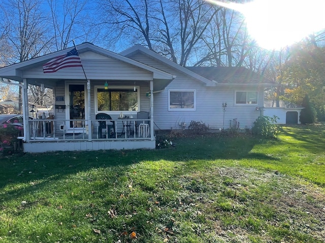 rear view of property featuring a lawn and covered porch