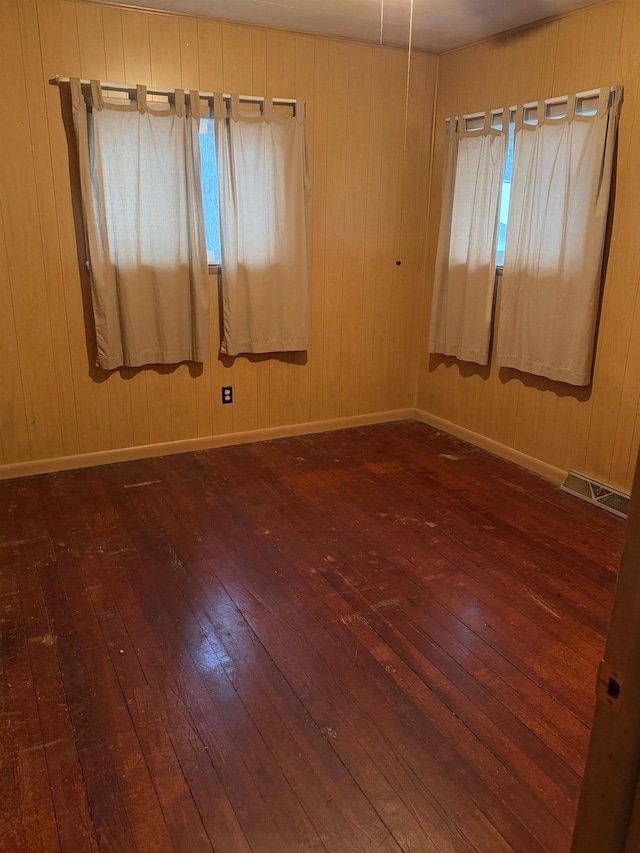 empty room featuring wood walls and dark wood-type flooring