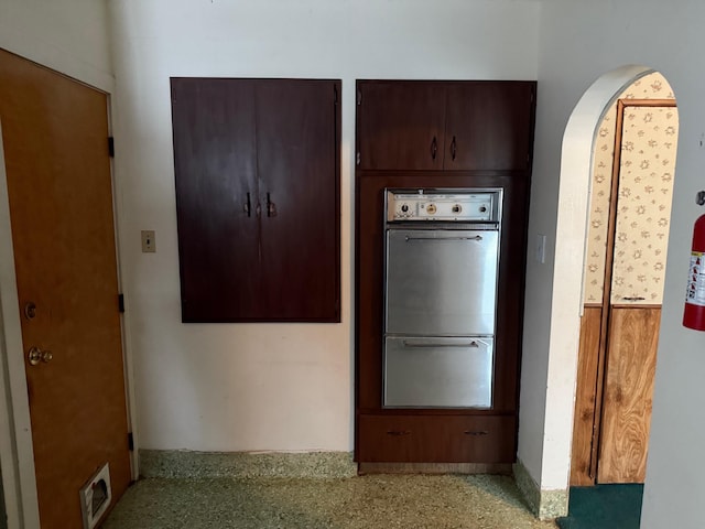 kitchen featuring multiple ovens and dark brown cabinets