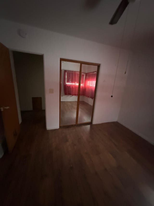 unfurnished bedroom featuring a closet, dark wood-type flooring, and ceiling fan