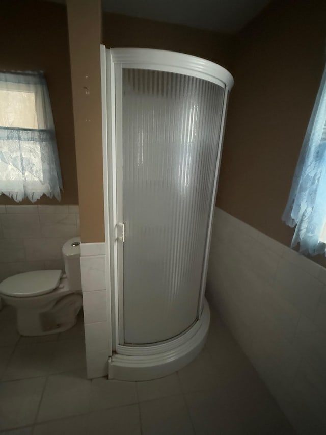 bathroom featuring tile patterned floors, tile walls, and a shower with shower door