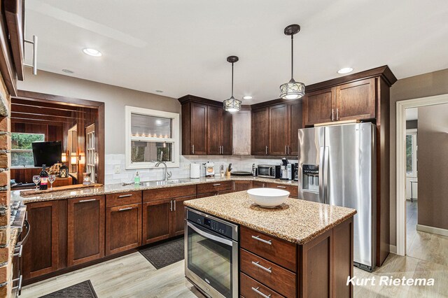 3205 Lakeshore Dr, Saint Joseph, MI 49085 - kitchen with stainless steel appliances, tasteful backsplash, light stone counters, a sink, and pendant lighting
