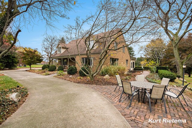 3205 Lakeshore Dr, Saint Joseph, MI 49085 - view of front facade with brick siding, outdoor dining space, a patio area, and roof with shingles