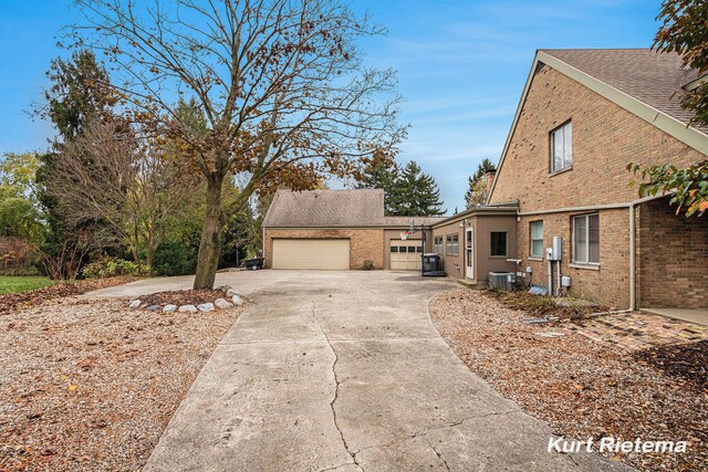 3205 Lakeshore Dr, Saint Joseph, MI 49085 - view of home's exterior featuring driveway, brick siding, a garage, and central AC