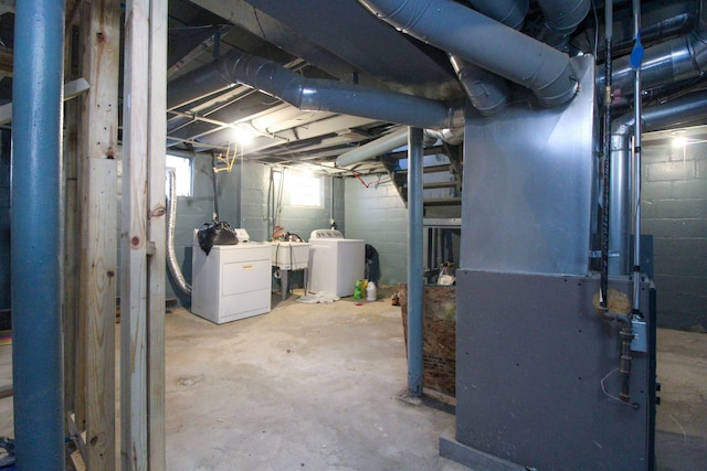 basement with washing machine and clothes dryer, heating unit, and sink