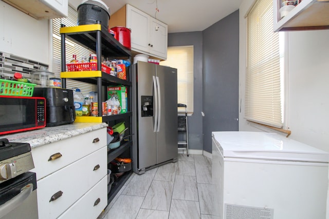 kitchen with white cabinets, appliances with stainless steel finishes, and tasteful backsplash