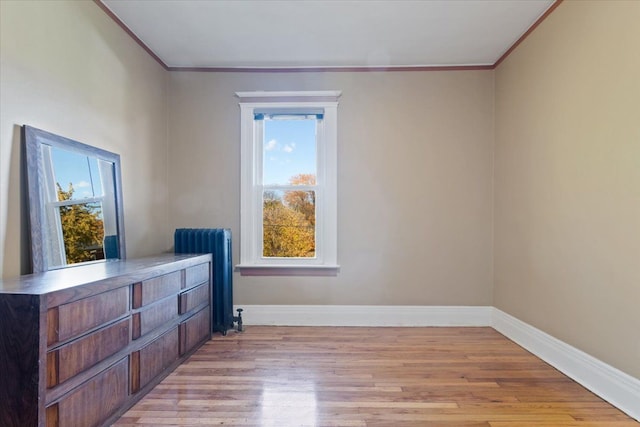 interior space with radiator heating unit, light wood-type flooring, and crown molding