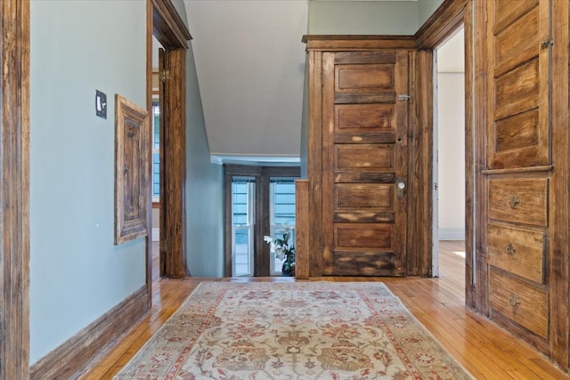 hallway with light hardwood / wood-style floors and lofted ceiling