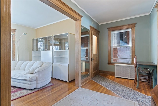 living area featuring hardwood / wood-style floors, radiator, and crown molding