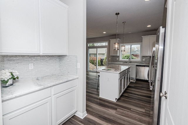 kitchen with hanging light fixtures, dark hardwood / wood-style flooring, decorative backsplash, white cabinets, and appliances with stainless steel finishes