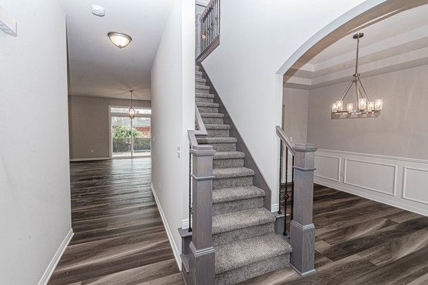 staircase with wood-type flooring and an inviting chandelier