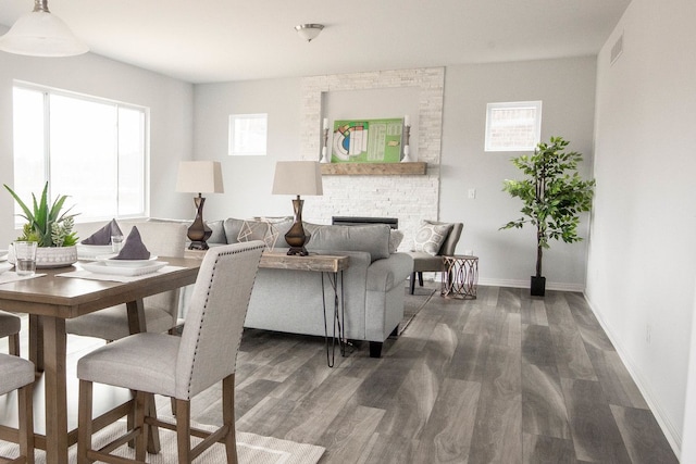 living room featuring dark hardwood / wood-style floors, a healthy amount of sunlight, and a stone fireplace