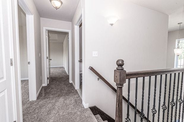 hallway featuring dark colored carpet and a chandelier