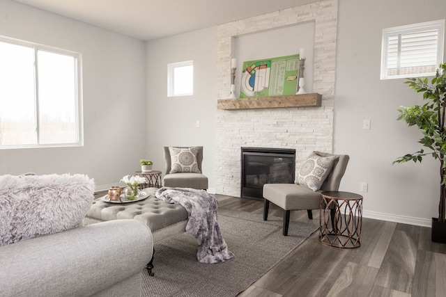 living room with dark hardwood / wood-style flooring and a stone fireplace