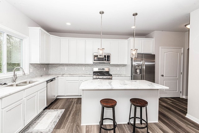 kitchen with a center island, dark hardwood / wood-style flooring, hanging light fixtures, and appliances with stainless steel finishes