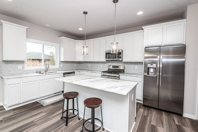 kitchen with pendant lighting, sink, a kitchen island, white cabinetry, and stainless steel appliances