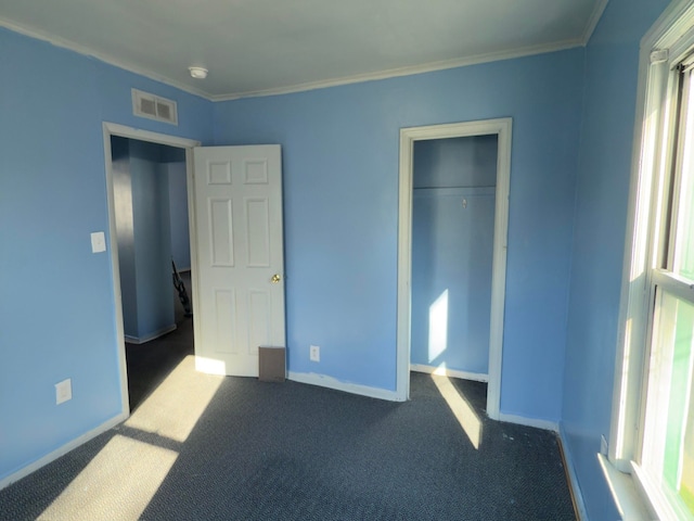 unfurnished bedroom featuring dark carpet, ornamental molding, and a closet