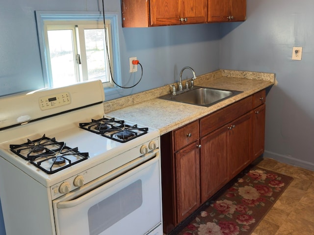 kitchen with white gas stove, light stone countertops, and sink