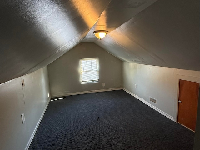 bonus room featuring dark carpet and vaulted ceiling