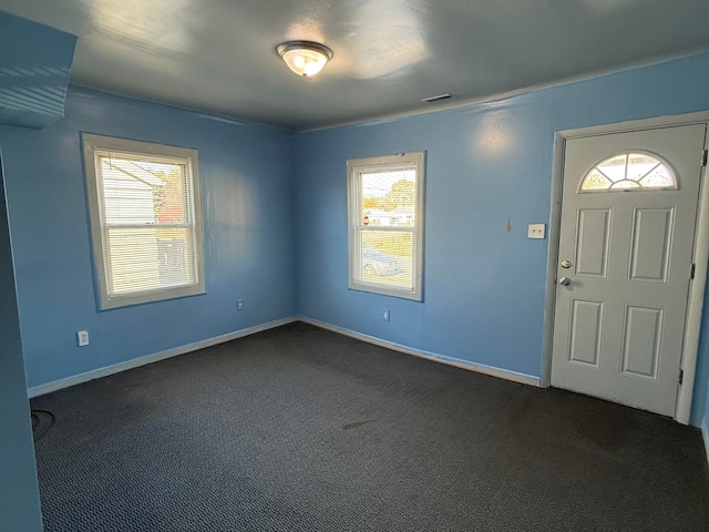 entryway featuring dark colored carpet and a wealth of natural light