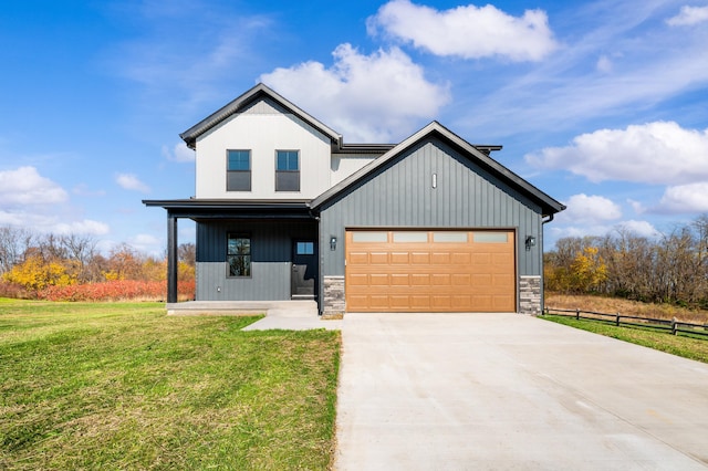 modern farmhouse featuring a front yard, stone siding, and driveway