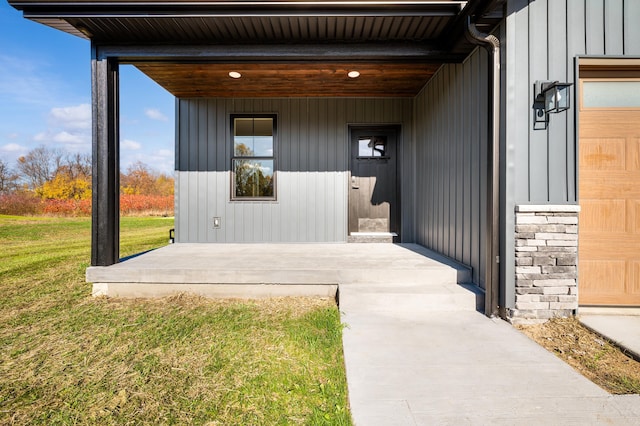 entrance to property featuring board and batten siding, a yard, and a garage