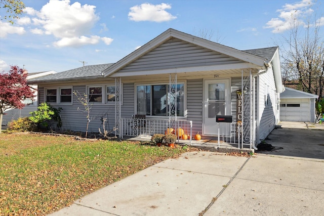 bungalow-style house with a porch, a garage, a front lawn, and an outdoor structure