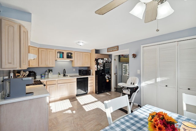 kitchen featuring ceiling fan, sink, black appliances, light brown cabinets, and range hood