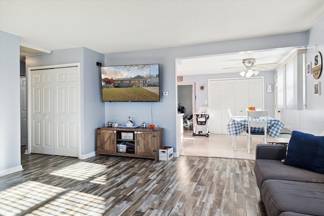 living room featuring ceiling fan and dark wood-type flooring