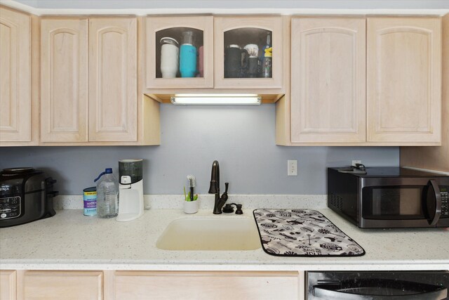 kitchen with light brown cabinets, black dishwasher, and sink