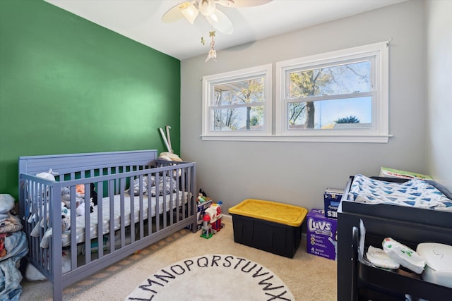 bedroom with a nursery area, carpet floors, and ceiling fan