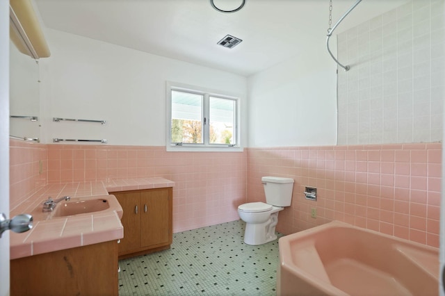 bathroom with tile patterned floors, vanity, tile walls, and toilet