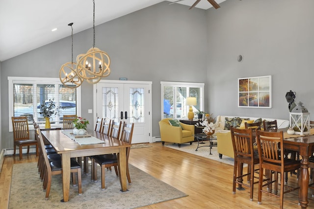 dining area with light wood finished floors, french doors, a notable chandelier, high vaulted ceiling, and a baseboard radiator