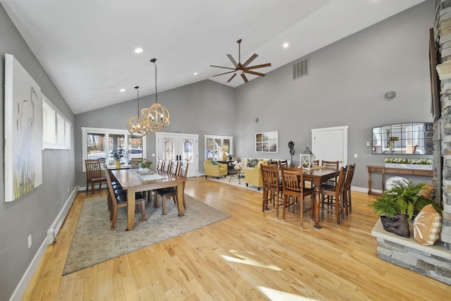 dining room featuring visible vents, baseboards, light wood-style flooring, high vaulted ceiling, and a baseboard radiator