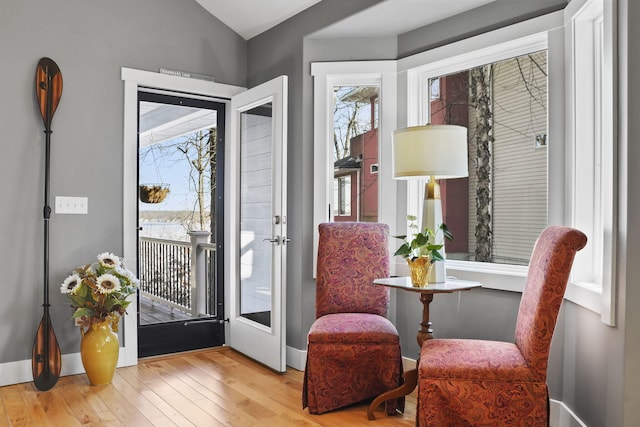 sitting room with baseboards, lofted ceiling, and hardwood / wood-style floors