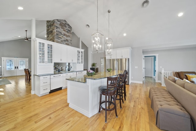 kitchen featuring visible vents, light wood-style flooring, glass insert cabinets, open floor plan, and a center island