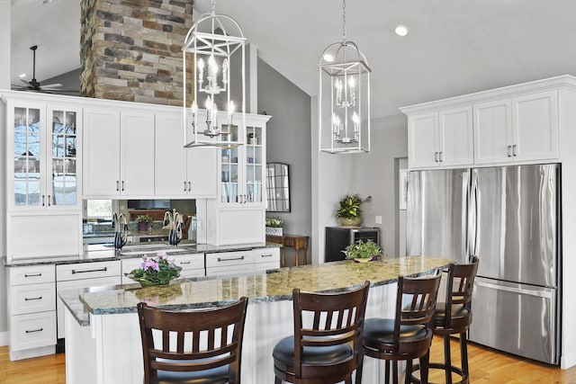 kitchen with ceiling fan, white cabinetry, freestanding refrigerator, and lofted ceiling