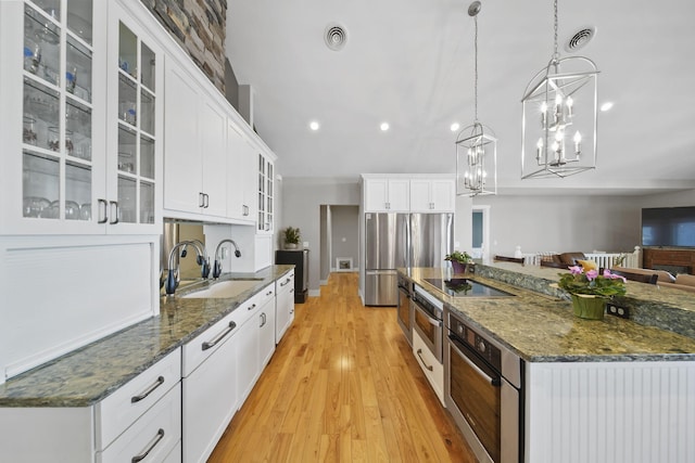 kitchen with visible vents, a large island with sink, light wood-style flooring, stainless steel appliances, and a sink