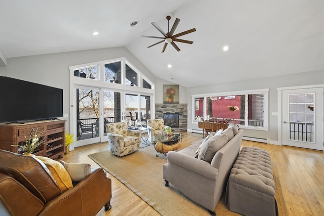 living room featuring visible vents, ceiling fan, a stone fireplace, wood finished floors, and a baseboard radiator